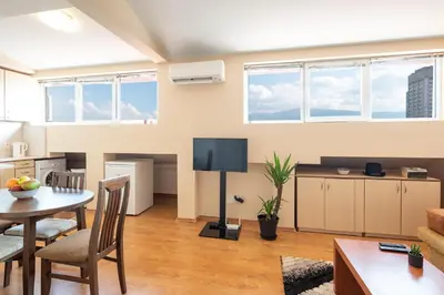 a living room with a table and chairs and a tv at Studio KFC in Sofia