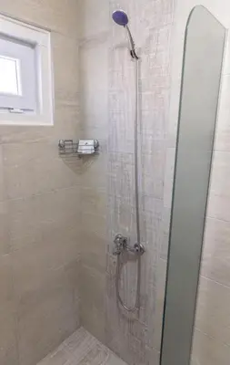 a shower with a glass door in a bathroom at Къщи за гости 