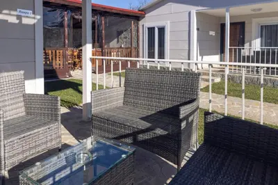 two chairs and a glass table on a balcony at Къщи за гости 