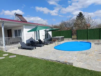 a pool with chairs and umbrellas in a yard at Къщи за гости 