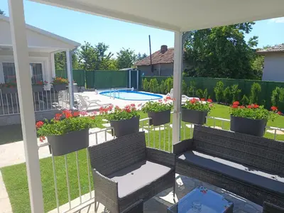 a screened in porch with a bench and flowers at Къщи за гости 