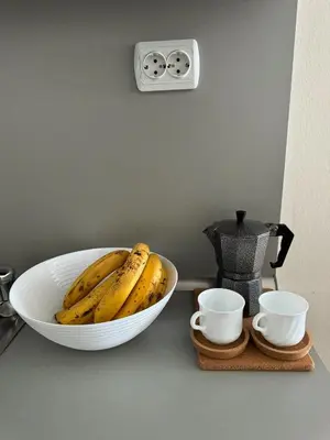 a bowl of bananas sitting on a counter with two cups at Gardenia Apartment Pamporovo in Pamporovo