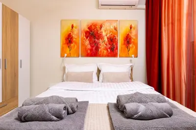 a bedroom with a bed with three paintings on the wall at City Park flat near to Medical University in Plovdiv