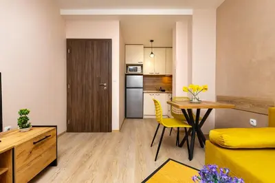 a small apartment with a kitchen and a table and yellow chairs at Central Lovely apartment Venu close to Old Town in Plovdiv