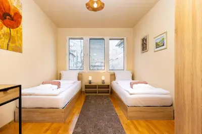 two beds in a room with two windows at Stancho's House 3BR apartment close to OLD TOWN & KAPANA district in Plovdiv