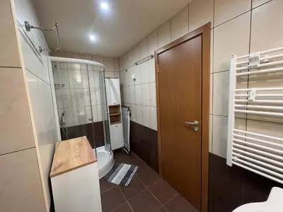 a bathroom with a toilet and a wooden door at Tulip Apartment High-End, Grand Resort Pamporovo in Pamporovo