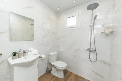 a white bathroom with a toilet and a shower at Apartment Velik in Sandanski