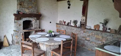 a dining room with a table and a stone fireplace at Капсъзовата къща in Leshten