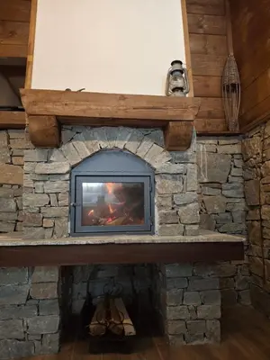 a stone fireplace with a television in it at Капсъзовата къща in Leshten