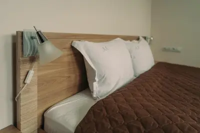 a bed with a wooden head board with a lamp at Apartment Aria 5 in Velingrad