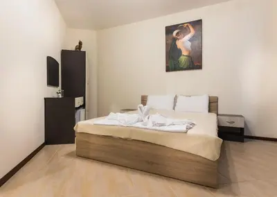 a bedroom with a bed with white sheets and a painting at Hotel-Restaurant DIMAX in Yoakim-Gruevo
