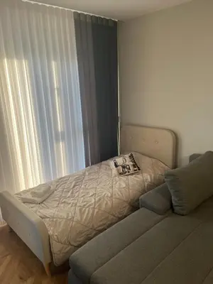 a bed in a room with a couch next to a window at City lux apartment in Plovdiv