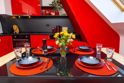 a kitchen with red cabinets and a black table with plates and utensils at Plovdiv Urban Gem 2BD Apartment by Flat Mаnаger in Plovdiv
