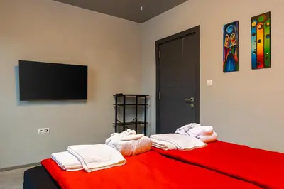 a bedroom with a red bed with a flat screen tv at Plovdiv Urban Gem 2BD Apartment by Flat Mаnаger in Plovdiv