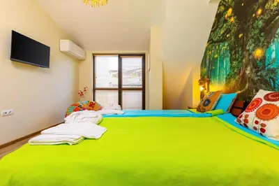 a bedroom with a green bed with a painting on the wall at Plovdiv Urban Gem 2BD Apartment by Flat Mаnаger in Plovdiv