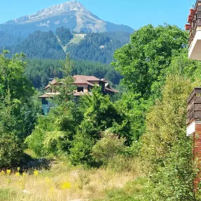a house on a hill with a mountain in the background at Cozy Mountain-View Apartment in Belmont, Bansko by Flat Mаnager in Bansko