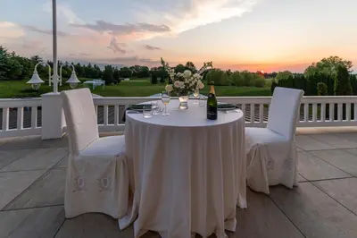 a white table with a bottle of wine and chairs at Saint Sofia Golf Club, Hotel and SPA in Robertowo