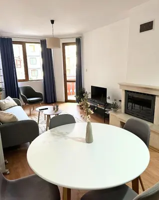 a living room with a white table and chairs at Ski Lift Apartment in Bansko