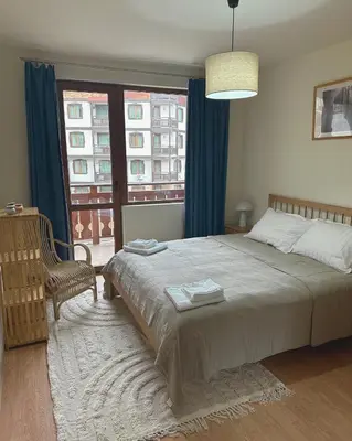 a bedroom with a bed and a chair and a window at Ski Lift Apartment in Bansko