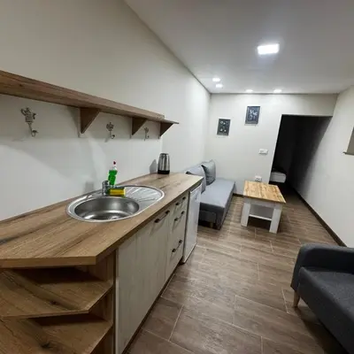 a bathroom with a sink and a living room at Апартаменти Белчини in Dobrinishte