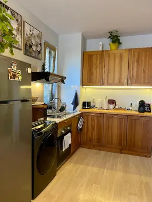 a kitchen with a black refrigerator and wooden cabinets at 2-room Forest Retreat - Fireplace, Veranda, BBQ, Views in Bansko