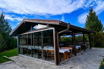 a gazebo with wooden tables and chairs at Хотел Валентино 2 in Dobrinishte