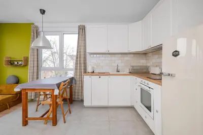 a kitchen with white cabinets and a table and a couch at Bright and Cozy 1BD Apartment plus Desk by Flat Mаnаger in Sofia