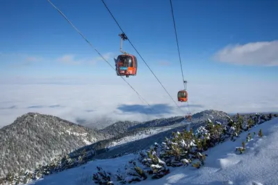 two ski lifts flying over a snow covered mountain at ТЕС Боровец Гарденс in Borovets
