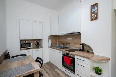 a kitchen with white cabinets and a wooden table at Central 1BD Next to Womens Market and Sofia's Gems by Flat Mаnаger in Sofia