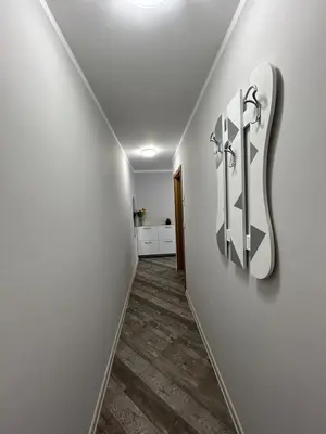 a hallway with a white wall with a guitar sign on it at Tanov Cozy Place in Blagoevgrad