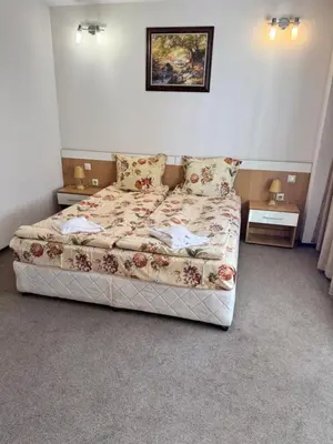 a bedroom with a bed with a floral bedspread at Хотел Добринище in Dobrinishte