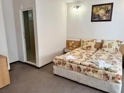 a small bedroom with a bed and a glass door at Хотел Добринище in Dobrinishte