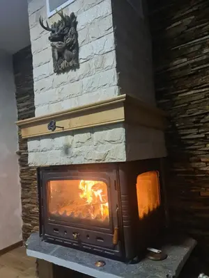 a stone fireplace with a fire in it at Къща за гости Джерман Guest house Dzherman in Sapareva Banya