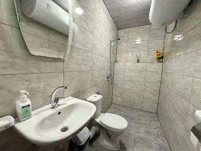 a white bathroom with a toilet and a sink at Guest House Mihalkovo in Mikhalkovo