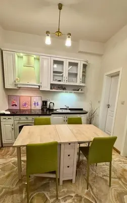 a kitchen with a wooden table and green chairs at 2 Bedrooms Top Central Apartment on Vitosha Boulevard in Sofia