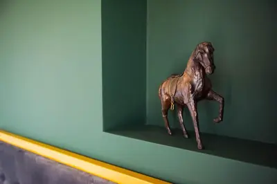 a wooden horse statue sitting on a green wall at Wonderland Rooms for Rent in Sofia