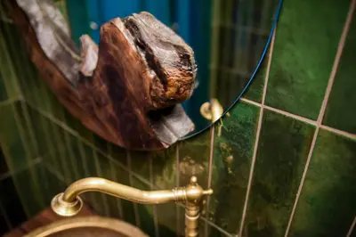 a mirror on the wall of a bathroom with a piece of wood at Wonderland Rooms for Rent in Sofia