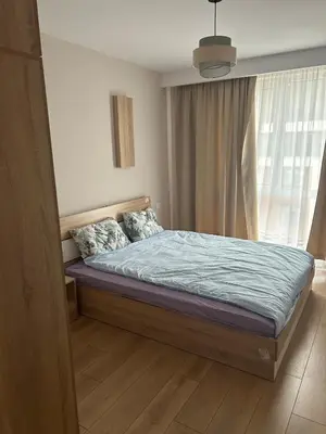 a bedroom with a bed with a blue comforter and a window at Cozy and comfortable panorama park Entrance E not K in Plovdiv