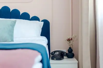 a bed with a blue headboard and a telephone on a night stand at Maison Colorée - Bright And Cozy Home by Metro And Mall in Sofia