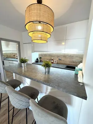 a kitchen with a long counter with chairs and a light fixture at Cozy Home In Central Plovdiv in Plovdiv
