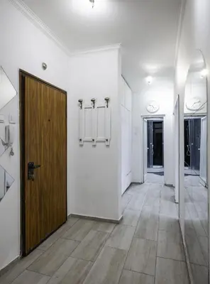 a hallway with a wooden door and white walls at The Cosmopolitan Shine 1-BDR Pet-Friendly Flat in Sofia