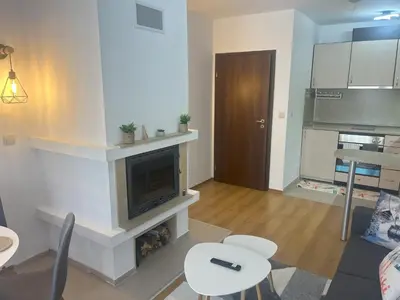 a living room with a fireplace and a table and chairs at Nest by the Peaks Apartment in Bansko in Bansko