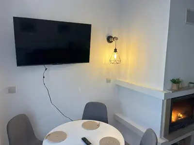 a room with a table and a tv and a fireplace at Nest by the Peaks Apartment in Bansko in Bansko