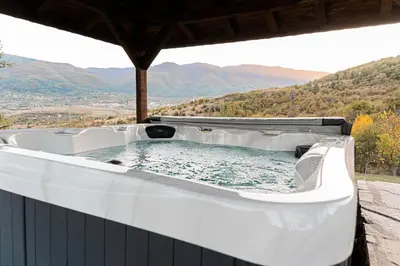 a hot tub on a deck with mountains in the background at Вила Китна in Lozno