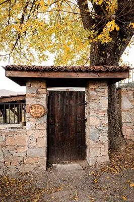 a stone building with a wooden door in front of a tree at Вила Китна in Lozno