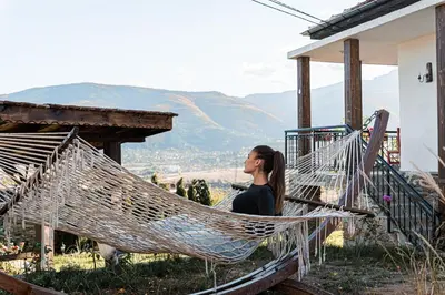a woman sitting in a hammock on a house at Вила Китна in Lozno