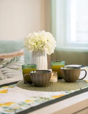 a table with three cups and a vase with flowers at Boho Floral Apartment near to Old Town in Plovdiv