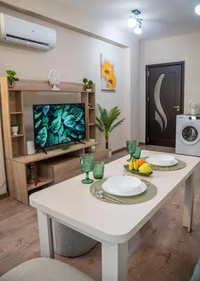 a living room with a white table and a tv at Boho Floral Apartment near to Old Town in Plovdiv