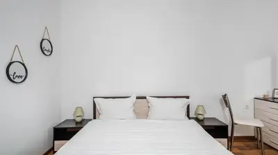 a bedroom with a white bed and a chair at Terra Vibes - Central 1BD with balcony by Flat Mаnager in Sofia