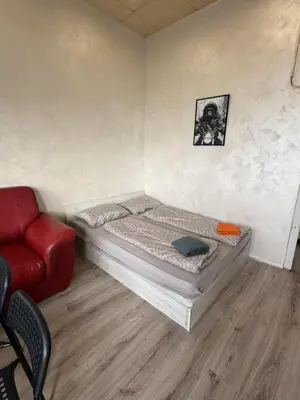 a small bedroom with a bed and a red chair at The Alpha in Sofia